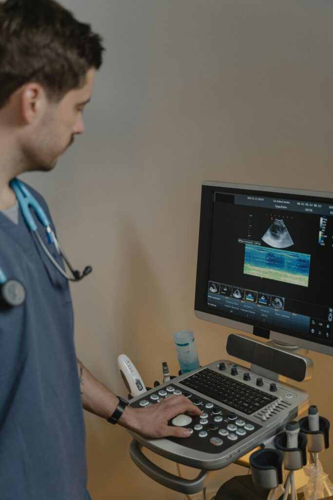 A male veterinarian examines an animal using an ultrasound machine in a clinical setting.